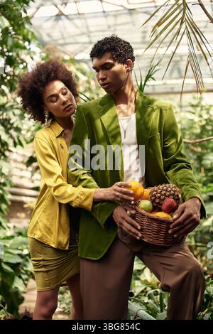 In einem üppigen Gewächshaus teilt sich ein fröhliches Paar eine zarte Umarmung, während es bunte Früchte pflückt. Stockfoto
