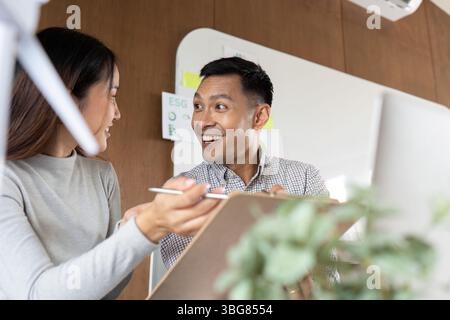Positive Interaktion. Zwei Kollegen tauschen Ideen aus und lächeln in einem gemeinsamen Büro. Stockfoto