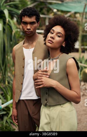 Ein junges Paar teilt einen Moment der Romantik, umgeben von verschiedenen Pflanzen in einem Gewächshaus. Stockfoto