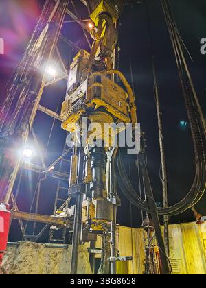Nahaufnahme von schweren Bohrgeräten, die nachts auf einer Industriebau arbeiten. Ölproduktion. Mobiles Foto. Stockfoto
