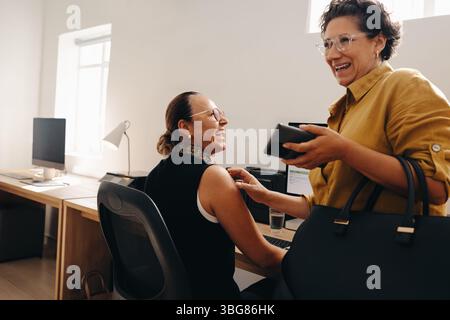 Zwei Kollegen teilen einen freudigen Moment, während sie in einer modernen Büroumgebung zusammenarbeiten, um ein Gefühl von Kameradschaft und Teamarbeit zu spüren. Stockfoto