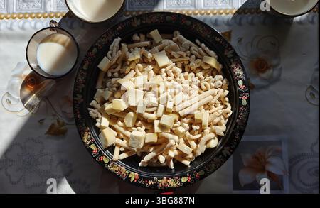 Genießen Sie ein traditionelles mongolisches Essen mit Käse und Quark-Knödeln, serviert auf einem wunderschön dekorierten Tablett mit Milch Stockfoto