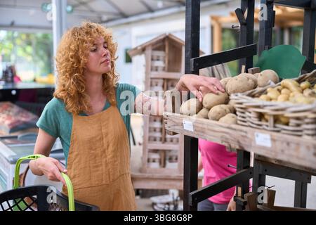 Frau, die Kartoffeln in einem nachhaltigen Lebensmittelgeschäft auswählt Stockfoto
