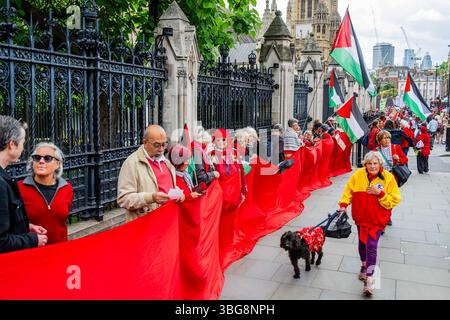 London, Großbritannien. Juni 2025. Eine Nothilfe-Demonstration für Palästina schafft eine rote Linie (mit Band und roten Outfits) um das Parlament während der Fragen des Premierministers, „jetzt ein vollständiges Waffenembargo und Sanktionen gegen Israel zu fordern“. Sie reagieren auf die anhaltende Invasion der israelischen Verteidigungskräfte in Gaza. Guy Bell/Alamy Live News Stockfoto