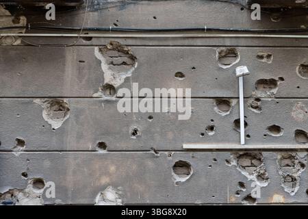 Eine alte Mauer voller Zeit und Kugeln schafft eine dramatische Textur voller verborgener Geschichten und einer Atmosphäre der Verlassenheit Stockfoto
