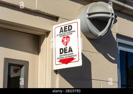 Upland, CA, USA - 15. Mai 2025: Ein automatisierter externer Defibrillator, AED, Schild in weiß und rot hängt über einer Tür in Chino Hills, Kalifornien. Stockfoto
