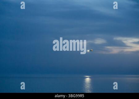 Ein Flugzeug, das nachts landet und über das Meer fliegt Stockfoto