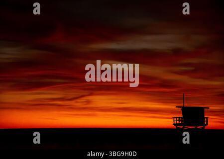 Ein Rettungsschirm-Turm ist vor einem dramatischen orangen Sonnenuntergang in Venice Beach in Südkalifornien geschildert Stockfoto
