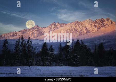 Mondaufgang hinter den schneebedeckten Gipfeln von Krivan, hohe Tatra bei Sonnenaufgang in der Slowakei Stockfoto