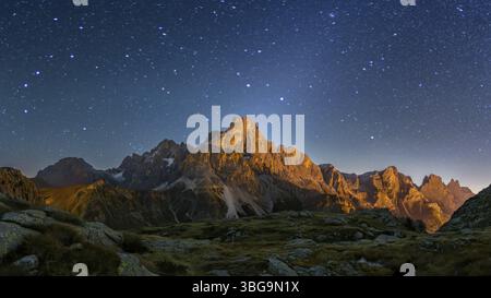 Der Berg Cimon delle Pala oberhalb des Passo Rolle mit Wolken bei Nacht mit Sternen und Tierkreislicht Stockfoto