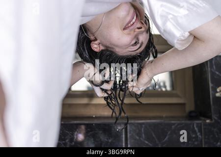 Nahaufnahme Porträt einer glücklichen jungen Frau, die zu Hause unter der Dusche ihr Haar wäscht. Schönheit und Körperpflege Stockfoto