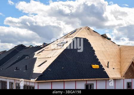 Der Prozess der Installation von schwarzen Dachschindeln an neuen Wohnhäusern Stockfoto