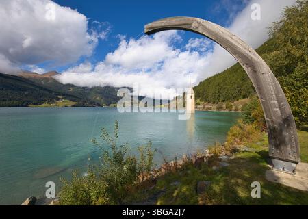Landschaft am Reschensee mit dem versunkenen Kirchturm unter einem Holzbogen. Stockfoto