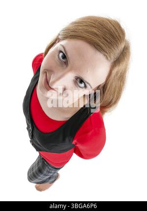 Extrem hoher Winkel in voller Länge von einer jungen blonden Frau in karierter Hose, rotem Pullover und schwarzer Weste auf weißem Hintergrund mit geneigtem Hea Stockfoto