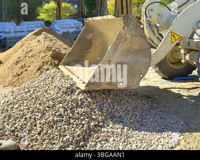 Baustelle, Baggerschaufel auf Kies, schwere Maschinen und Baumaterialien im Freien, wichtige Zuschlagstoffe für Bau und Entwicklung Stockfoto