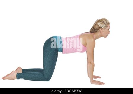 Yoga-Bildserie: Seitliche Ganzkörperansicht einer blonden Frau in Yoga-Pose Katzenviereckige Pose (Majariasana), die vor einem weißen Rücken nach vorne blickt Stockfoto