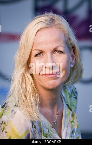 Kopfporträt einer blonden Frau mittleren Alters, die freundlich vor einer gemalten Wand in die Kamera lächelt Stockfoto