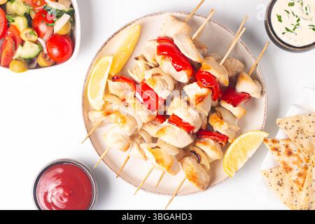 Gegrillte Hähnchenspieße. Satay mit Zitrone und Salat. Kebab mit Saucen. Stockfoto