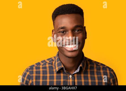 Nahaufnahme Porträt von positiven jungen afroamerikanischen Kerl aufrichtig lächelnd Bei der Kamera Stockfoto