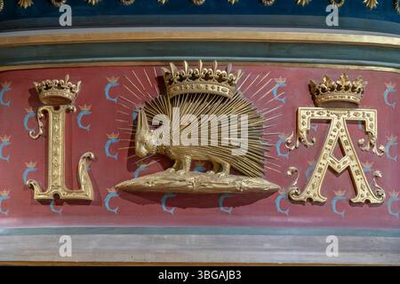 Das goldene Louis XII Monogramm mit strahlendem Sonnenschliff ziert die prunkvolle königliche Zeremoniendekoration im historischen château. Stockfoto