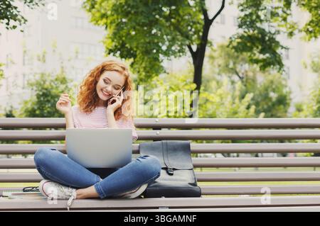 Frau, die am Laptop arbeitet und mit ihrem Smartphone spricht Stockfoto