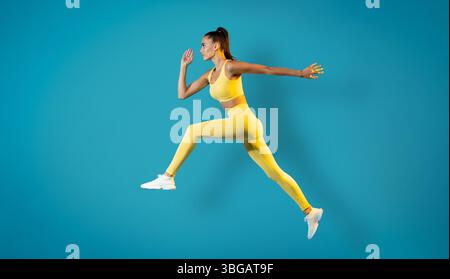 Athletische Frau, Die In Der Luft Auf Blauem Hintergrund Posiert Stockfoto