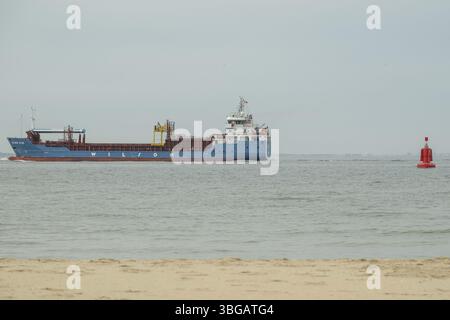 Disheok, zeeland, niederlande, Nordsee, Frachtschiff segelt auf ruhigen Gewässern, vorbei an einer roten Boje, mit einem Sandstrand im Vordergrund Stockfoto
