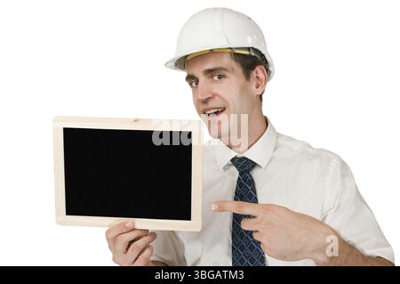 Frontaler Oberkörperschuss eines jungen Mannes in weißem Hemd und weißem Helm, der eine kleine Tafel hochhält, mit dem Zeigefinger gegen A Stockfoto
