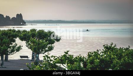Beschreibung: Motorboot fährt beim Sonnenaufgang über den ruhigen See. Konstanz, Bodensee, Baden-Württemberg, Deutschland, Europa. Stockfoto