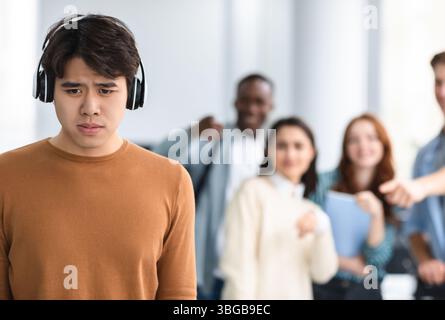 Die Leute spotten und machen sich über traurigen asiatischen Mann lustig Stockfoto