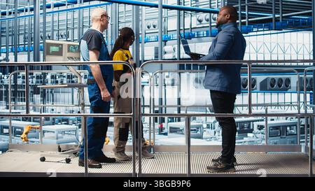 Investor besucht Solarpaneele der Industrie 4,0 und spricht mit Ingenieuren, um vor der Investition eine begrenzte Ausfallzeit zu gewährleisten. Photovoltaik Smart Factory Aktionärsüberprüfungen Arbeiten von Technikern, Kamera A Stockfoto