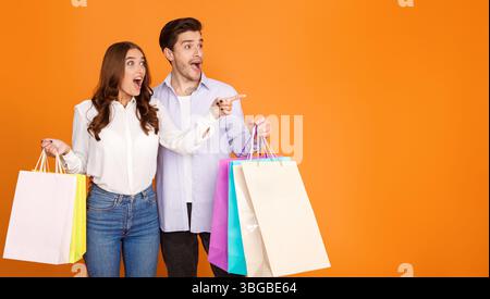 Wow-Angebot. Schockiertes Paar, das mit den Fingern auf freien Raum zeigt Stockfoto