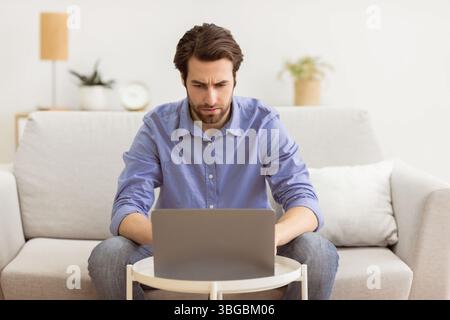 Der Mann, Der Mit Dem Laptop Runzelte, Hatte Probleme, Auf Dem Sofa Im Hotel Zu Sitzen Stockfoto