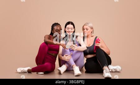 Fitness-Tracking-App Drei Multiethnische Frauen In Sportswear, Die Zusammen Smartphone Verwenden Stockfoto