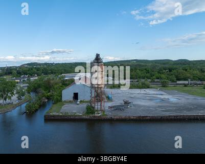 Verlassenes verrostetes Silo mit Wendeltreppen in Hudson, New York. Überwachsene Vegetation und verfallende Industriestruktur deuten auf eine vergessene Vergangenheit hin. Stockfoto