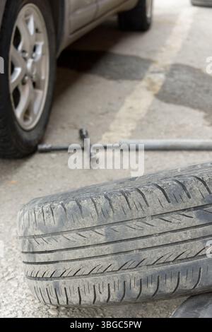 Reifenwechsel am Straßenrand. Daneben befindet sich ein Platten Reifen auf dem Boden Stockfoto