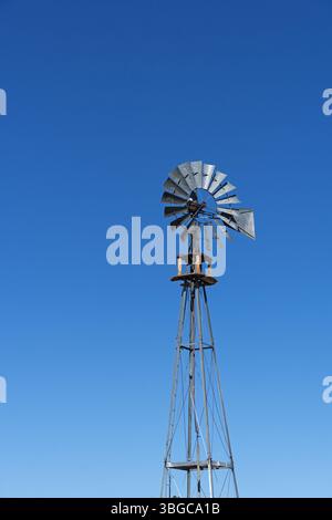 Galvanisierte Metallwindmühle für einen Brunnen mit blauem Himmel Hintergrund und Copyspace Stockfoto