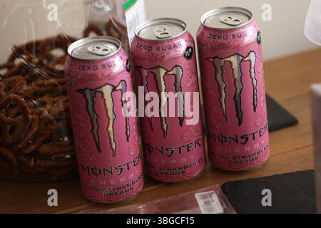 Drei Dosen rosa Monster Energy Drink auf einem Tisch in Burgess Hill, East Sussex, Großbritannien. Stockfoto