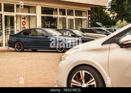 Mailand, italien 4. juni 2025, moderne getunte Autos parken vor einem Gebäude mit großen Fenstern, die die Leidenschaft der Automobile und den urbanen Stil zum Ausdruck bringen Stockfoto
