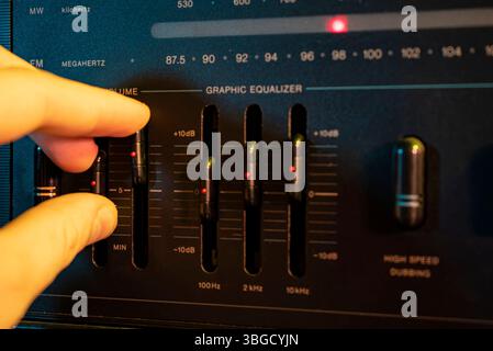 Tontechniker, der den grafischen Equalizer auf einem Vintage-Audiomixer anpasst Stockfoto