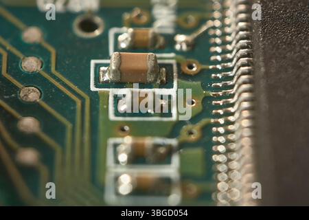 Makrofoto in Nahaufnahme, in dem elektronische Bauteile auf eine Leiterplatte aufgelötet werden und Technologie und Komplexität veranschaulichen Stockfoto