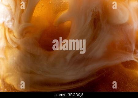 Nahaufnahme der Milch, die in einem Glas in einen Eiskaffee gegossen wird Stockfoto