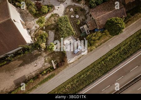 Von oben nach unten aus ist ein ruhiger Wohnbereich mit Häusern, Gärten, einem geparkten Auto und einer nahe gelegenen Autobahn zu sehen Stockfoto