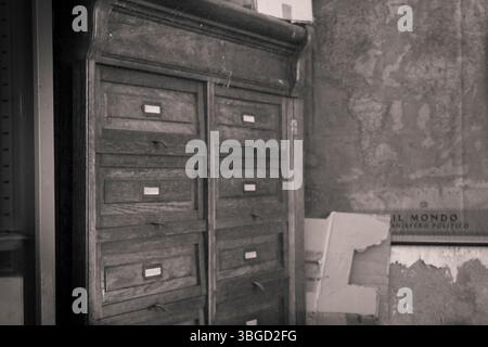 Ein Vintage-Aktenschrank aus Holz steht in einem verfallenen Raum und erweckt ein Gefühl von Geschichte und Verlassenheit Stockfoto