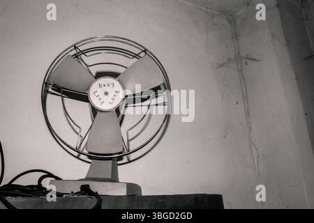 Vintage lasa Ventilator an einer weißen Wand montiert, der Luft in einer schwarz-weißen Komposition umwälzt Stockfoto