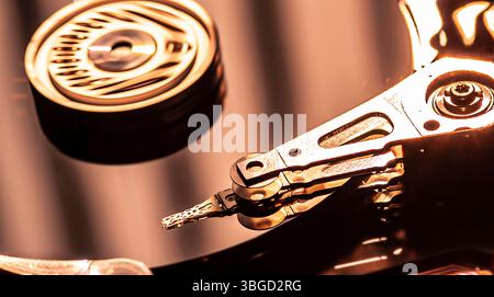 Nahaufnahme der Festplatte, die Daten liest, mit warmem Licht, das auf der Platte reflektiert, wodurch ein Hightech- und Datenspeicherkonzept entsteht Stockfoto
