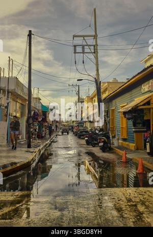 Isla Mujeres, Mexiko 1. Januar 2025: Pfützen spiegeln bunte Gebäude und Stromleitungen entlang einer Straße in isla mujeres, mexiko, nach dem Regen Stockfoto