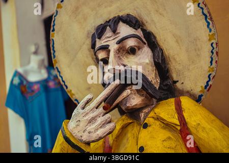 Valladolid, Mexiko 1. Januar 2025: Traditionelle Holzstatue eines mexikanischen Mannes mit Sombrero und rauchender Zigarre, die die mexikanische Kultur in vall repräsentiert Stockfoto