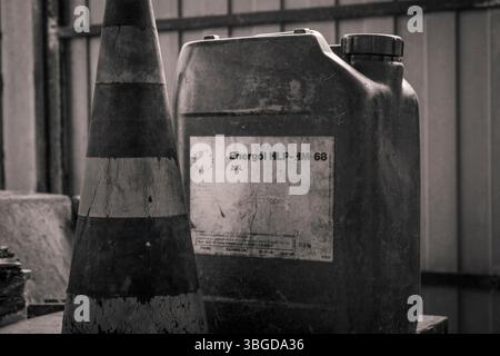 Mailand, Italien 1. Januar 2025: Schwarzweißfoto eines Verkehrskegels und eines schmutzigen Kunststoffkanisters in einer verlassenen Industrieumgebung Stockfoto