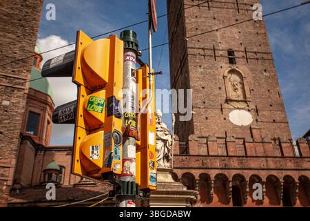 Bologna, Italien 1. Januar 2025: Gelbe Ampel mit Aufklebern auf der piazza porta ravegnana, bologna, mit dem mittelalterlichen torre degli asinelli i. Stockfoto